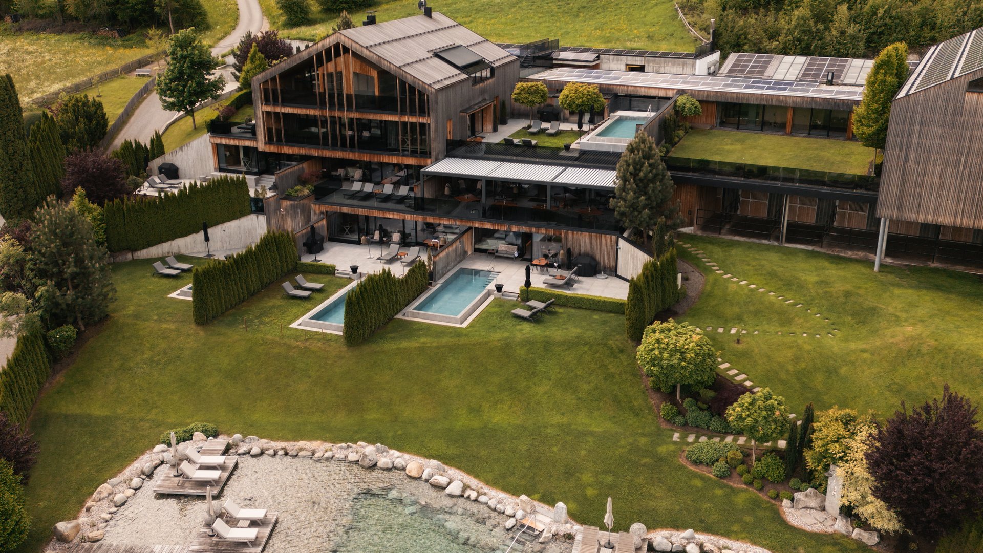 Veduta aerea di un hotel moderno con piscina naturale e paesaggio verde