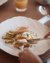 Person cutting poached egg with avocado and toast on white plate