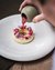 Hand pouring red sauce on an artistically decorated dessert plate