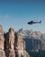 Elicottero vola vicino a ripide rocce in paesaggio montano