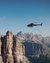 Helicopter flying near steep rocks in mountainous landscape