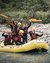 Group of six people happily rafting on a river in a yellow inflatable boat