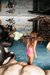 Bambina con costume rosa gioca nell'area giochi d'acqua con scultura di mucca