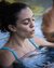 Frau entspannt im Wasser eines Pools mit geschlossenen Augen