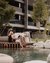 Couple relaxing by water with book on terrace in front of modern building