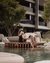 Couple relaxing by water with book on terrace in front of modern building