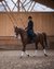 Woman riding a brown horse in an indoor riding arena