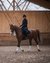 Woman riding a brown horse in an indoor riding arena