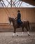 Woman riding a brown horse in an indoor riding arena