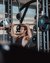 Man lifting weights in gym with trainer spotting