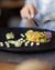 Fein angerichtete Gemüseterrine auf schwarzem Teller mit Wein und Besteck
