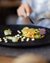 Finely plated vegetable terrine on black plate with wine and cutlery