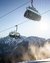 Ski lift with passengers in front of snowy mountains under a sunny sky