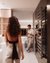 Woman in foreground, man at end of hallway in modern room