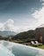 Infinity pool with mountain view next to modern wooden house and sun loungers
