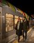 Couple walking past a lit train at the station at night
