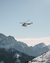 Hubschrauber fliegt über schneebedeckte Berglandschaft bei klarem Himmel