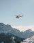 Helicopter flying over snowy mountain landscape under clear sky