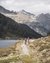Due ciclisti su un sentiero di montagna accanto a un lago con montagne sullo sfondo