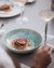 Person holding fork and wine glass near plate with meat and vegetables