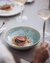 Persona con forchetta e calice di vino davanti a piatto con carne e verdure