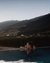 Donna rilassata in piscina al tramonto con vista sulle montagne