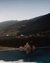Donna rilassata in piscina al tramonto con vista sulle montagne