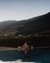 Frau entspannt im Pool bei Sonnenuntergang mit Bergblick