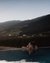 Woman relaxing in pool at sunset with mountain view