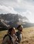 Two hikers with backpacks on a mountain overlooking snow-capped peaks