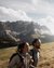 Two hikers with backpacks on a mountain overlooking snow-capped peaks